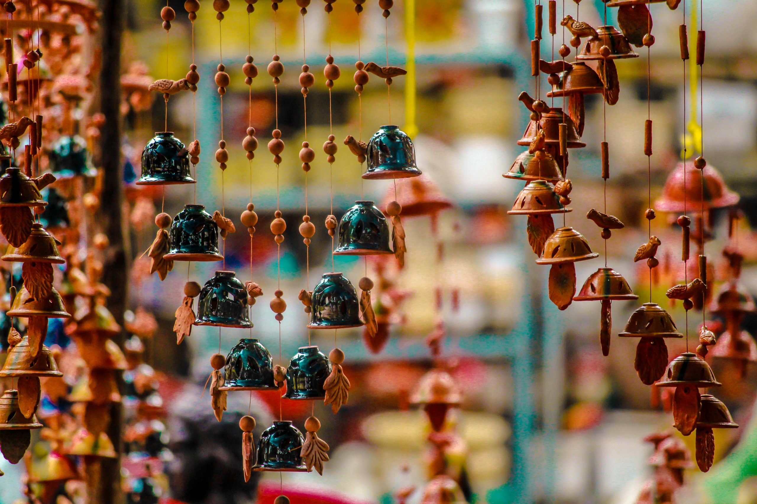 Home Vibrant hanging bells and ornaments in a pottery market stall, showcasing cultural artistry.