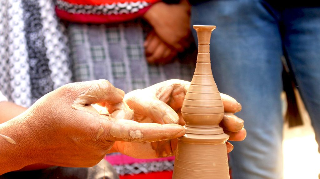 Home Close-up of artisan shaping a delicate clay vase with hands, showcasing skill and tradition.